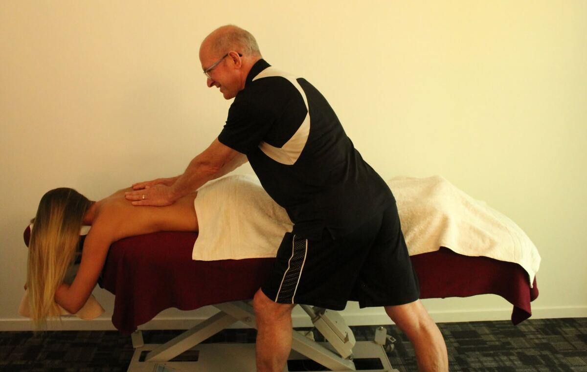 Roger giving a back massage to a client lying face down on the treatment table