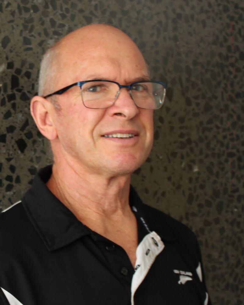 Roger White, massage therapist, smiling in his black work polo